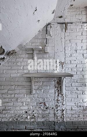 Peeling white paint on brick wall with shelf, interior of dilapidated old building, Philadelphia Pennsylvania USA