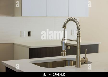 Installing new sink tape in the kitchen plumber with island sink Stock Photo