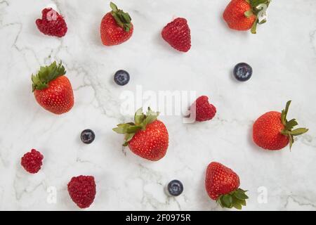 Fresh berries on white marble background flatlay. Raspberries, blueberries and strawberries pattern. Stock Photo