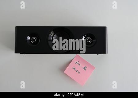Closeup loudspeaker placed on white wooden table next to sticky note with message face the music, high angle view Stock Photo