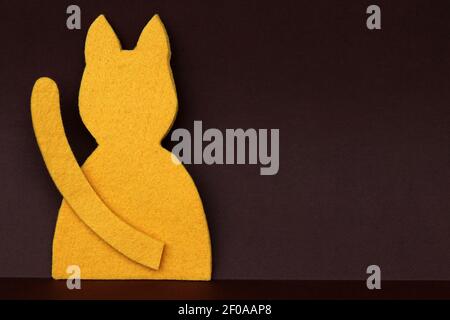 A yellow cat made of felt against a brown paper background Stock Photo