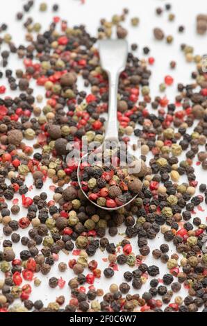 Mixed peppercorns and spoon on a white background Stock Photo
