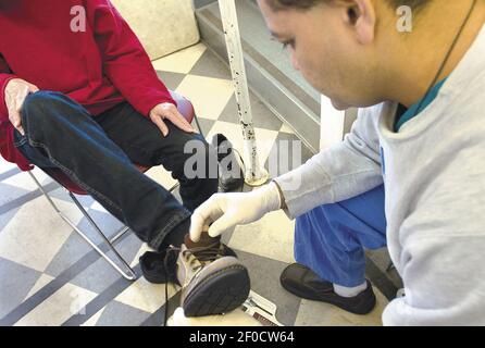 Dr. Nicholas Abidi fits a shoe onto a patient s foot November 25