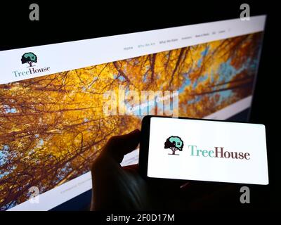 Person holding smartphone with logo of US food processing company TreeHouse Foods Inc. on screen in front of website. Focus on phone display. Stock Photo