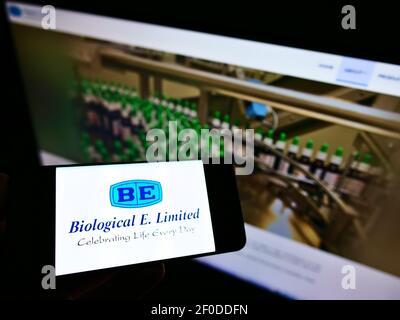 Person holding smartphone with logo of Indian biopharmaceutical company Biological E. Limited on screen in front of website. Focus on phone display. Stock Photo