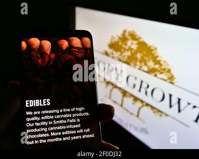 Person holding cellphone with webpage of Canadian cannabis company Canopy Growth Corporation on screen with logo. Focus on center of phone display. Stock Photo