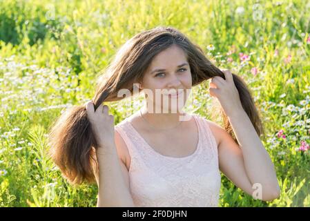 Girl holding long hair on flower meadow Stock Photo