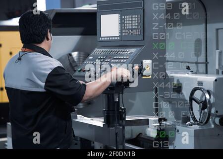 Industrial technician operating CNC lathing machine. CNC programming code. Metalworking manufacturing factory Stock Photo