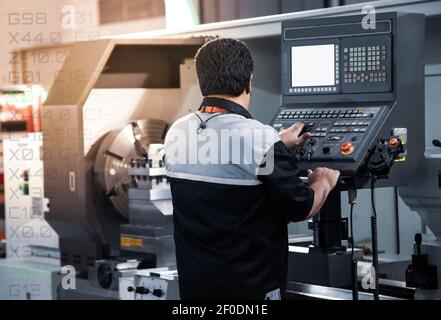 Industrial technician operating CNC lathing machine. CNC programming code. Metalworking manufacturing factory Stock Photo