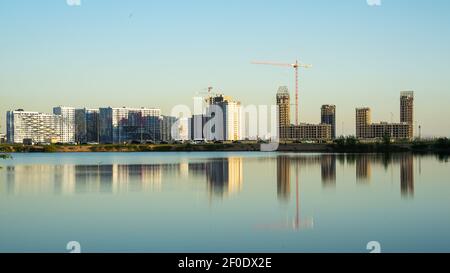 New residential blocks and buildings under construction, with cranes visible; reflected in the city pool, St. Petersburg, Russia Stock Photo