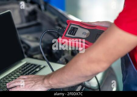 Male hands conducting car diagnostics using computer Stock Photo