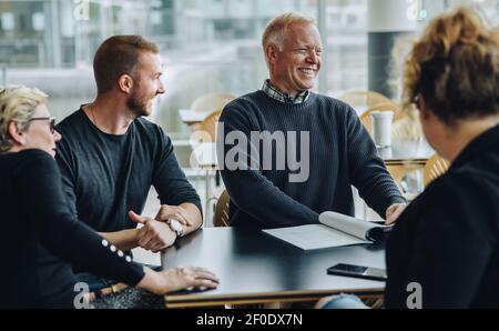 Smiling senior businessman having meeting with team. Business people discussing a contract and smiling in boardroom. Stock Photo