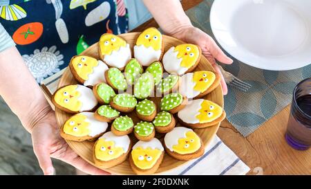 Table setting for Easter. Baking ideas with kids. Iced cookies for Easter in the form of chickens in an eggshell. The concept of family comfort and ho Stock Photo