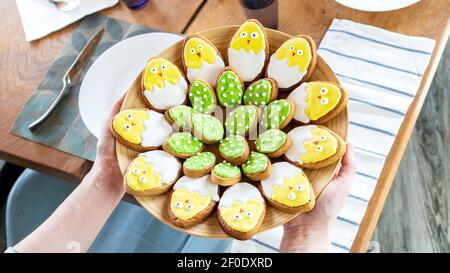 Iced Easter cookies on a large platter. Serving the festive table. Unusual ideas for family baking with children. Easter cookies in the form of cute c Stock Photo