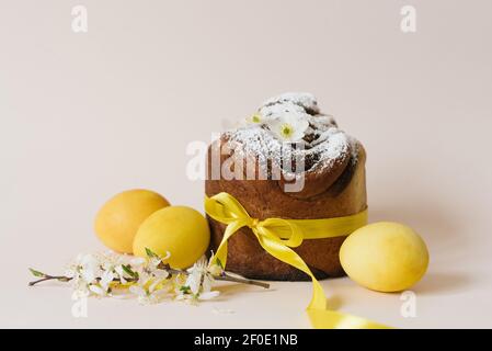 Easter composition of sweet bread cake, white flowers and yellow eggs on a light background. Orthodox Easter bread. A festive breakfast concept with s Stock Photo