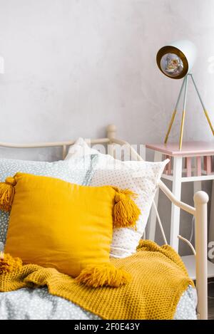 Close-up of the orange pillow, the headboard in the bedroom and the night light near the bed in the bedroom interior Stock Photo