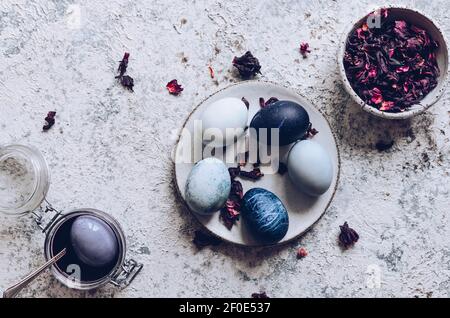 Dyed Easter eggs with marble stone effect painted with natural dye carcade tea from hibiscus flowers on grey concrete background. Top view. Stock Photo