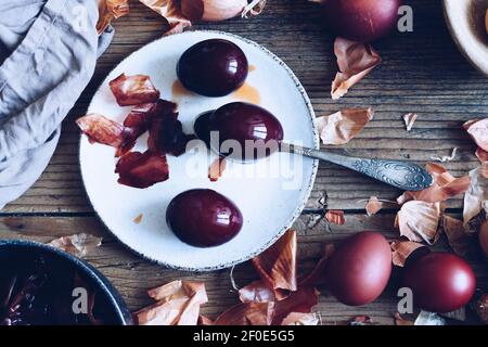 Dyed Easter eggs painted with natural dye onion on rustic wooden background. Process of dyeing eggs with natural paints for Easter. Natural ecological Stock Photo