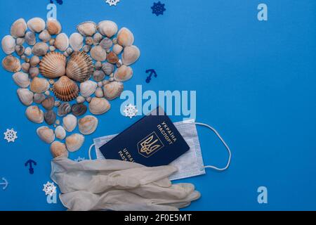 Heart-shaped shells on a blue background. Medical mask, biometric passport of Ukraine, medical gloves. Flat lay, mock up,  Stock Photo