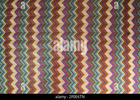 The pattern on the knitted fabric is a herringbone made of multi-colored stripes. Stock Photo