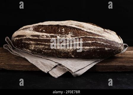 Freshly baked homemade artisan sourdough rye bread on wooden board. Closeup of farmhouse bread at leaven. Low key Stock Photo