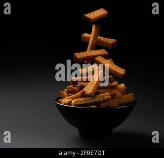 Falling rye bread croutons on black background Stock Photo
