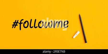 The word follow me or hashtag followme hand written with a black marker pen on yellow background. Stock Photo