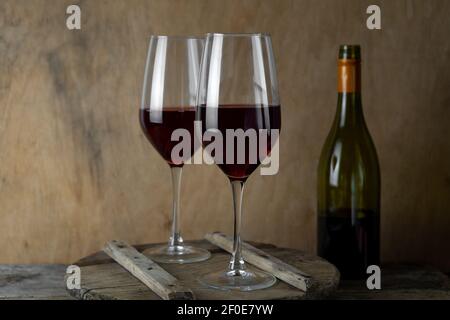 Two glasses of red wine. The bottle of wine is on the table. Wine background. Still life. Alcoholic drink in a glass. Wooden background. Stock Photo