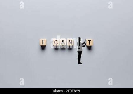 Silhouette of a hand drawn man changing the word I can't into I can by pushing away the letter. Aspiration, positivity, belief and motivation concept Stock Photo