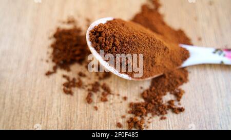 Coffee powder in the Spoon isolated on table wooden background. Pile of brown coffee spilling on ground, Top view, Indian spices Stock Photo