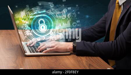 Business hand typing on a modern laptop with lock icon coming out from multimedia screen, intuitive technology concept Stock Photo