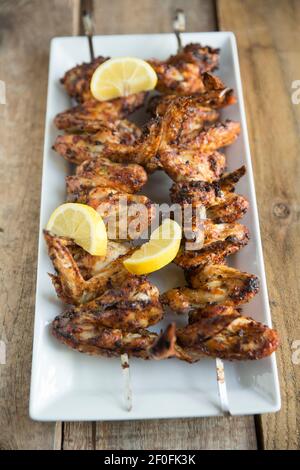British chicken wings that have been skewered and grilled after marinading in a Lebanese spice mix. Garnished with sliced lemons. England UK GB Stock Photo