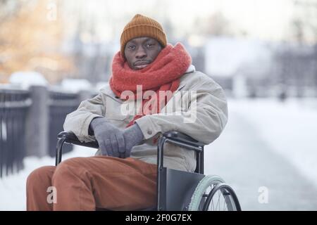 Portrait of African American man using wheelchair outdoors in winter and looking at camera , copy space Stock Photo