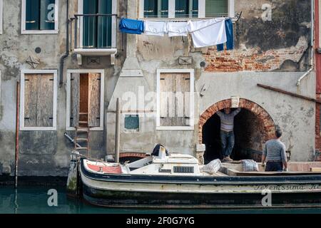 Venice, Italy. Workmen taking a break from work on a construction boat on a canal Stock Photo
