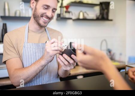 Smiling man in apron writing with marker on glass Stock Photo