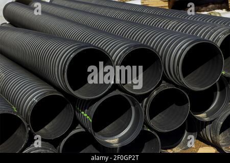 Plastic PVC pipes stacked main black pipes on heap of polyethylene pipes for a drain supply system for laying of city communications Stock Photo