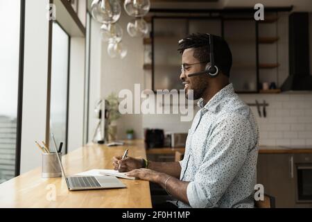 Side view confident African American man wearing headphones taking notes Stock Photo