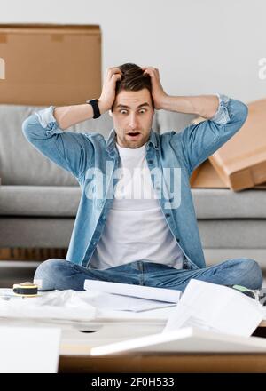 Frightened facial expression, difficult instructions and problems in assembling furniture Stock Photo