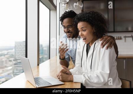 Close up overjoyed surprised African American couple reading good news Stock Photo