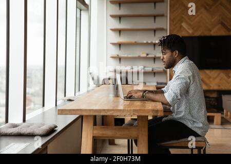 Side view African American man using laptop in modern apartment Stock Photo