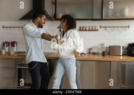 Happy African American couple dancing in kitchen, having fun Stock Photo