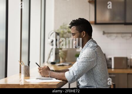 Side view smiling African American man wearing glasses using smartphone Stock Photo