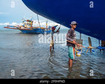Maintenance work being done on a traditional fishing boat with outriggers in Tinoto, a fishing village in Maasim, Sarangani Province of the Philippine Stock Photo