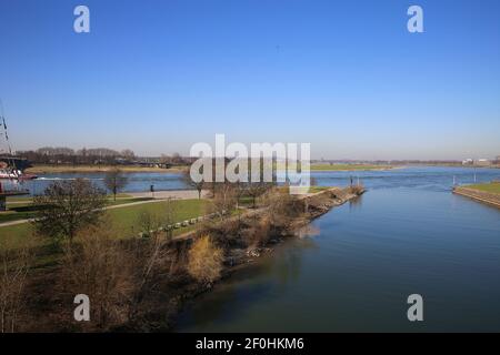 View over green pasture pensinsula (Mühlenweide) at river rhine against blue sky in winter - Duisburg, Germany Stock Photo