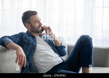 Relaxed man having conversation on phone, home interior Stock Photo