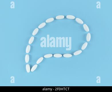 Speech bubble made from white tablets on blue backdrop with copy space. Stock Photo