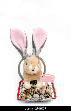 Easter banny and quail eggs in mini shopping basket on white background. Online trade. Shopping over the Internet Stock Photo