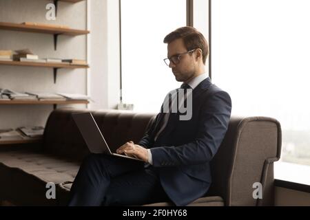 Close up confident businessman wearing glasses and suit using laptop Stock Photo