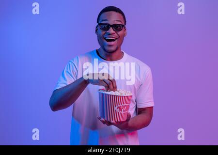 Portrait Of Emotional Black Guy In 3D Glasses With Bucket Of Popcorn Stock Photo