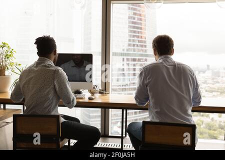 Back view diverse colleagues employees sitting at desk in office Stock Photo